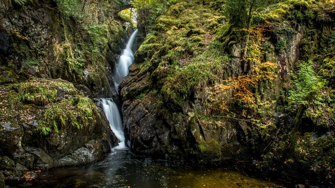 Waterfall cascading between green mossy rocks.